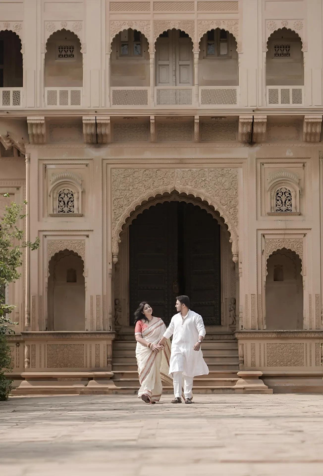 Wide pre-wedding portrait of the couple in a heritage courtyard