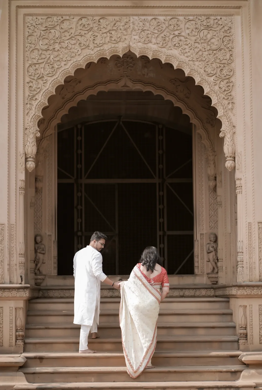 Couple walking hand in hand up palace steps