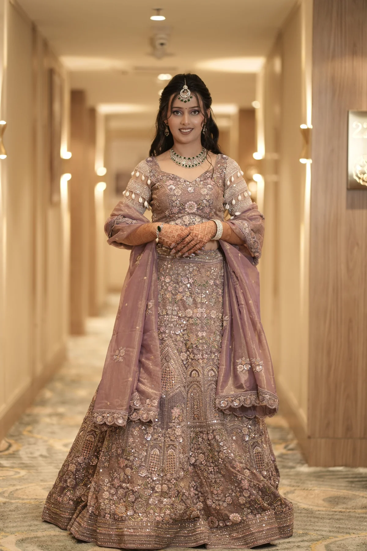 Bride in mauve lehenga in a softly lit corridor