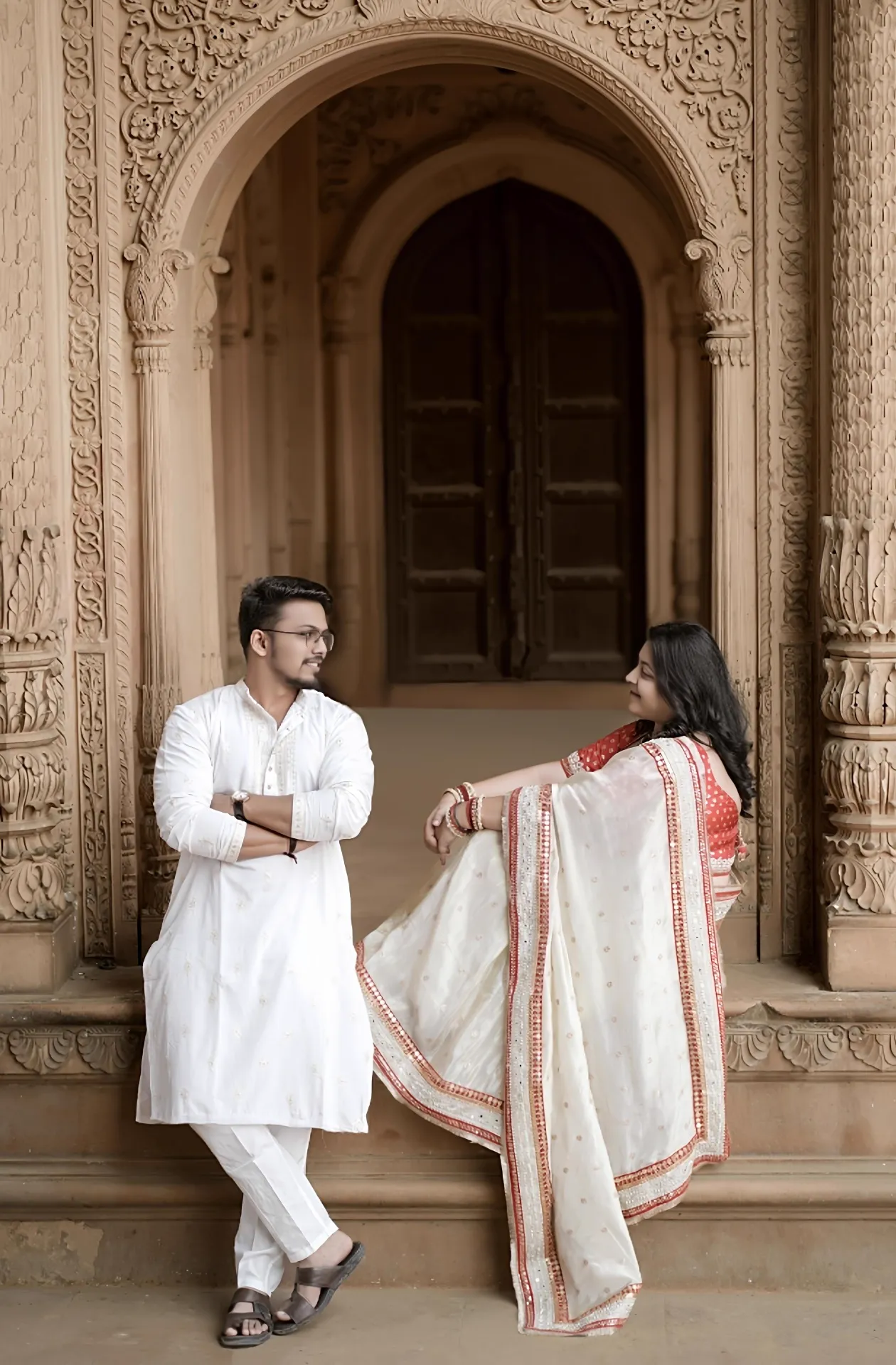 Couple posing under an ornate carved sandstone arch